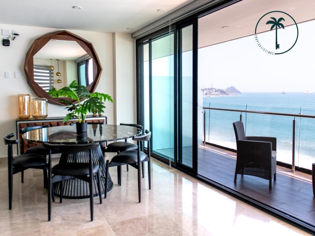 a dining room with a table and chairs and a view of the ocean at Moderno condominio con vista al mar! in Mazatlán