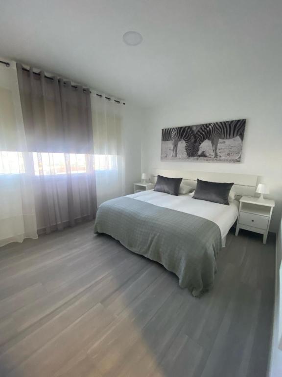 a white bedroom with a large bed and a zebra picture on the wall at Casa BagaCera "Baga" in Ingenio