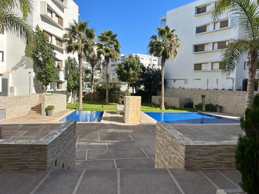 a courtyard with a swimming pool in front of a building at Appartement haut standing résidence Iken Parc Agadir Founty in Agadir