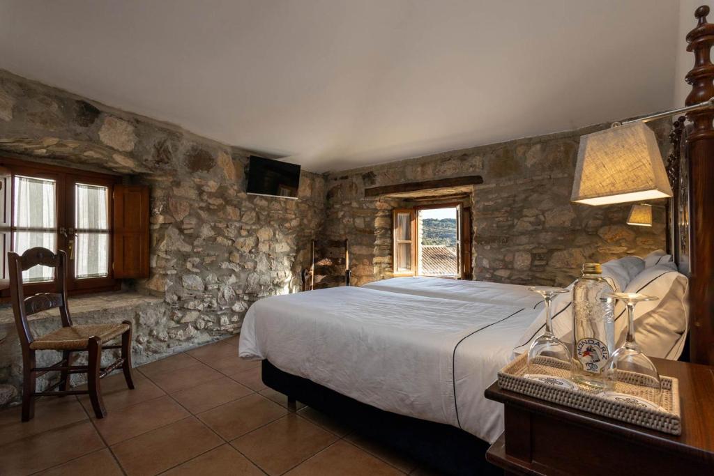 a bedroom with a bed and a stone wall at Tugasa Hotel La Posada in Villaluenga del Rosario