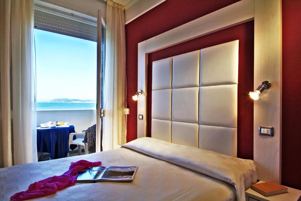 een slaapkamer met een bed en uitzicht op de oceaan bij Color Alexandra Plaza Family Hotel in Riccione