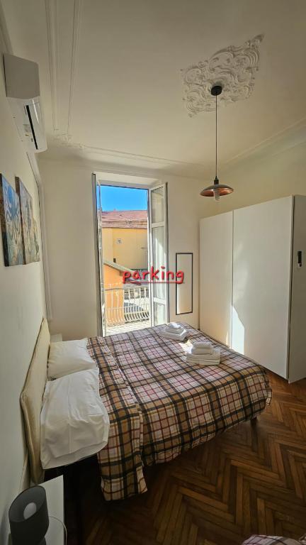 a bedroom with a bed with a plaid blanket and a window at Appartamenti Fiore in Sanremo