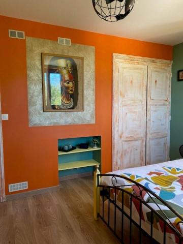 a bedroom with an orange wall with a bed and a mirror at Le Moulin du Modon in Couffy
