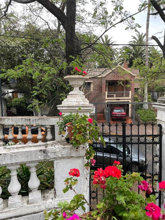 Une clôture avec des fleurs et une maison dans l'établissement Departamento en Casco Historico, à San Isidro
