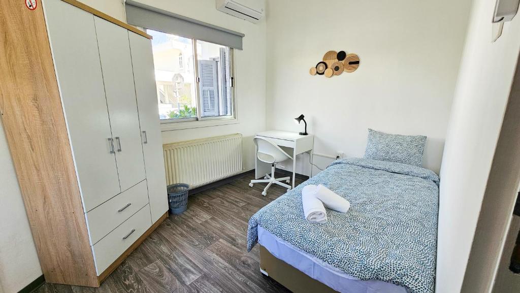 a bedroom with a bed and a desk and a window at The Lemon Tree Hostel in Larnaca