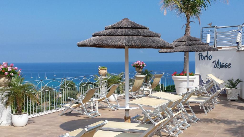 a patio with chairs and umbrellas and the ocean at Residence Porto Ulisse in Parghelia