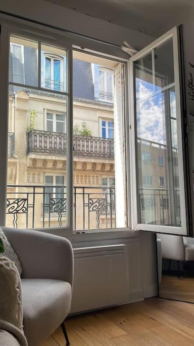 un salon avec un canapé et une grande fenêtre dans l'établissement Louis’ haven, à Paris