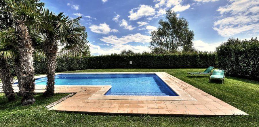 una piscina en un patio con una palmera en Duplex Torremirona Resort, en Navata