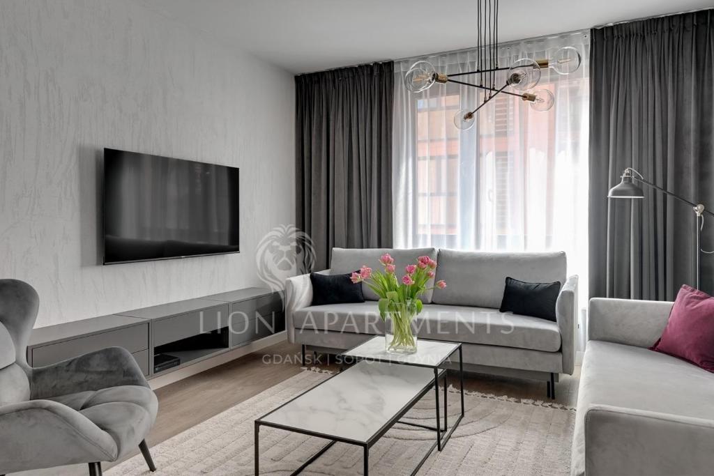 uma sala de estar com um sofá e uma televisão em Lion Apartments - SCALA City Center Premium Apartments ID em Gdansk