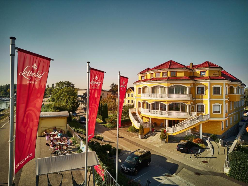 ein gelbes Gebäude mit roten Flaggen davor in der Unterkunft Donauhotel Lettnerhof in Au an der Donau