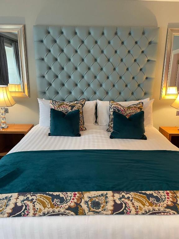 a large bed with a blue padded headboard and pillows at Headfort Arms Hotel in Kells