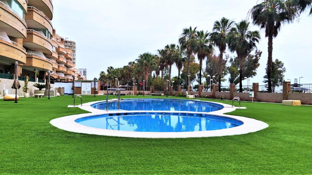 een groot zwembad in het midden van een grasveld bij ACV- Costa Marina I-1ªlinea planta 5 norte in Oropesa del Mar