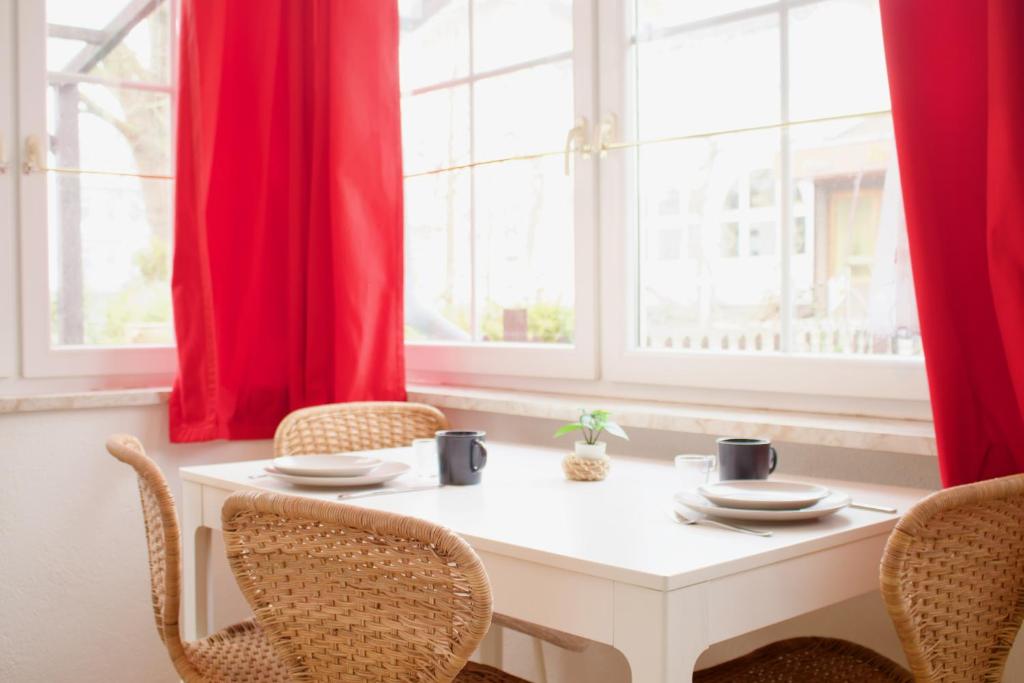 une table blanche avec des chaises dans une chambre avec des fenêtres dans l'établissement Strandvogtei Sellin - FeWo 5 - sehr zentrales großes Apartment, à Sellin