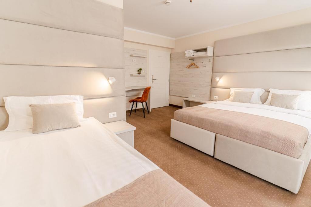 Habitación blanca con 2 camas y escritorio. en Pensiunea Elisei, en Timisoara