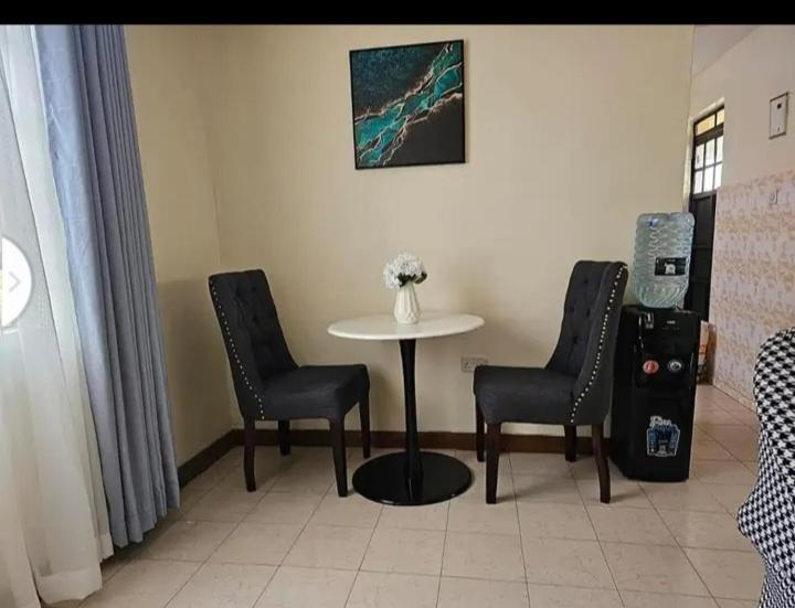 una habitación con una mesa y dos sillas y un jarrón con flores en Vanquish luxury, en Nairobi