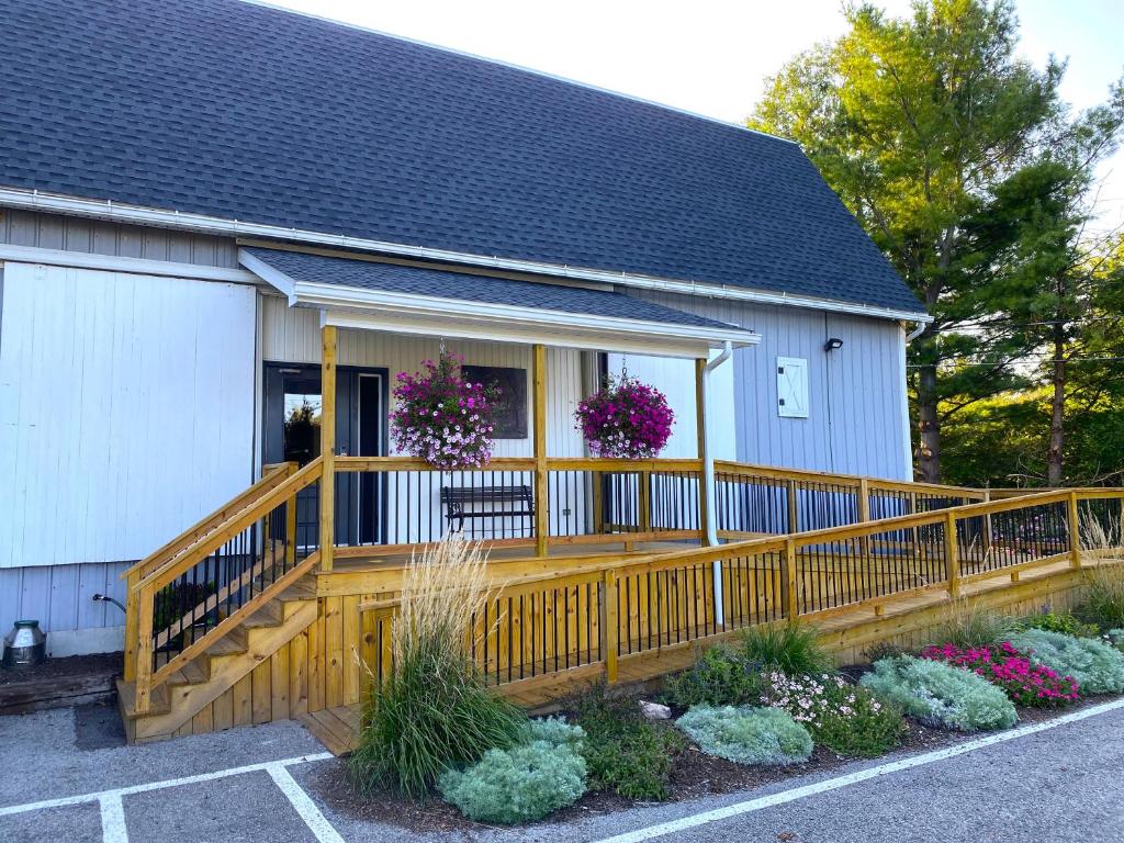 une maison avec une véranda en bois ornée de fleurs dans l'établissement Lake Ontario Motel & Inn, à Newfane