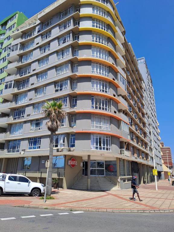 Un homme se promène devant un grand immeuble d'appartements dans l'établissement Unit 103 Tenbury, à Durban