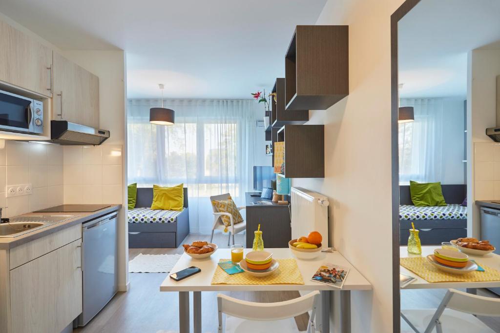 a kitchen and living room with a table and chairs at Résidence Nemea, Villeneuve Pont de Bois in Villeneuve d'Ascq