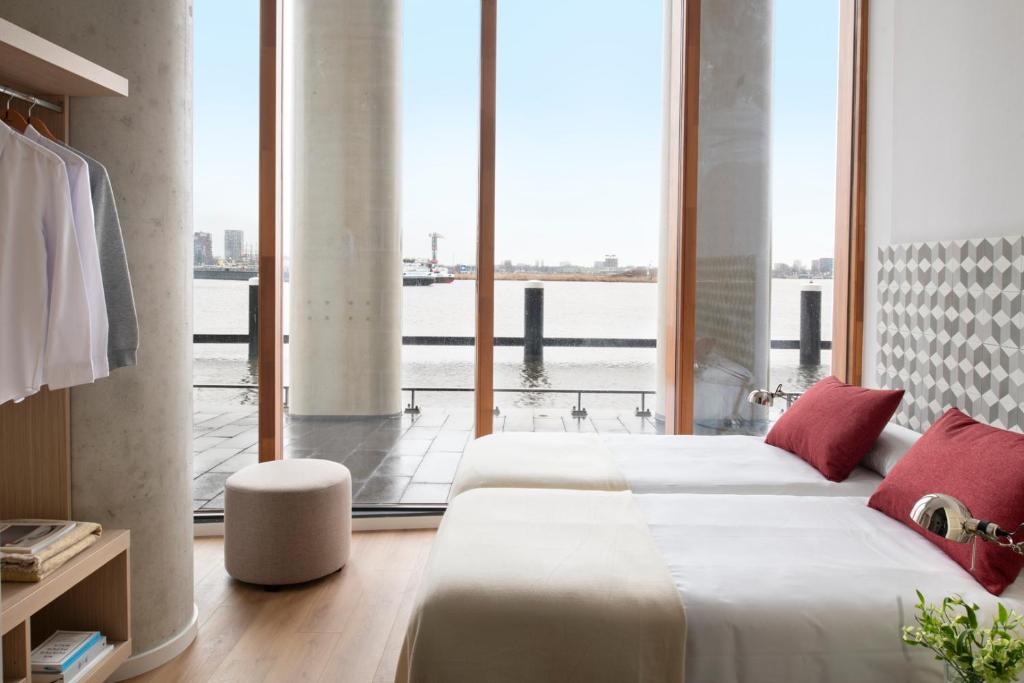 Eric Vökel Boutique Apartments - Riverfront Suites في أمستردام: غرفة نوم بسريرين ونافذة كبيرة