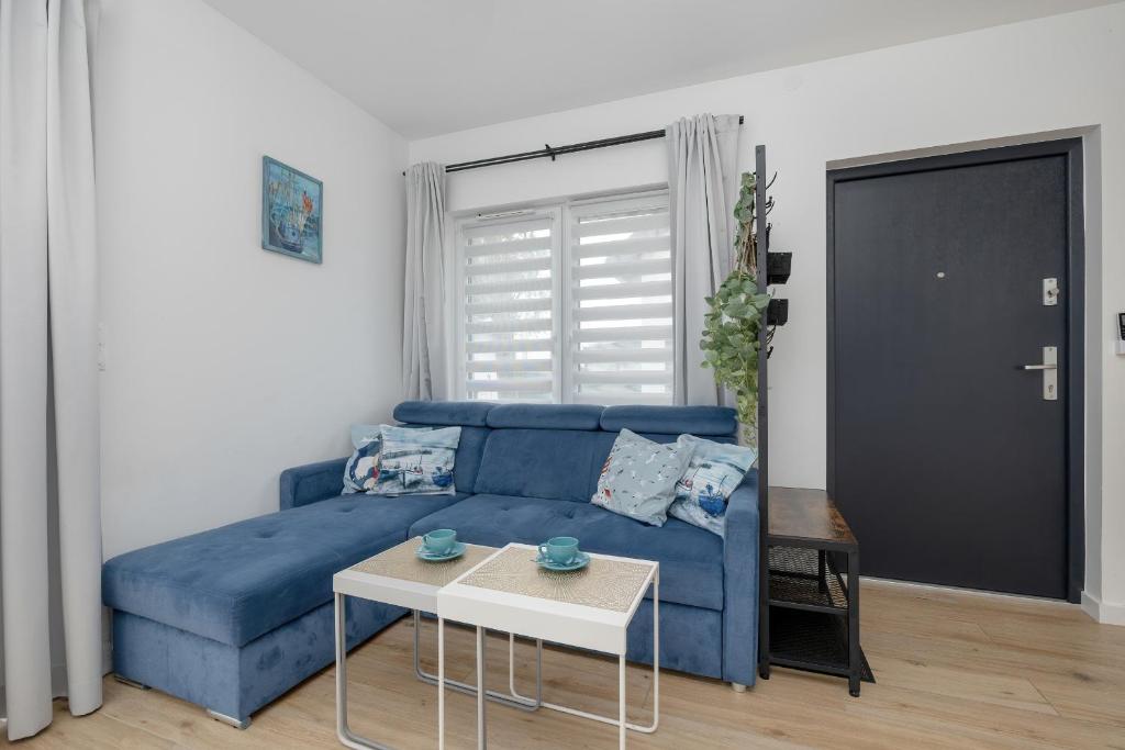 Sofá azul en la sala de estar con mesa en Apartment with Garden 450 m to the Beach by Rent like home, en Dziwnówek