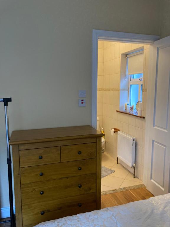 a bedroom with a wooden dresser and a bathroom at Woodside in Nenagh