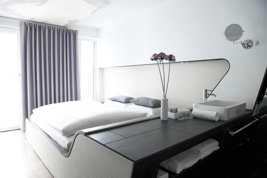 a white bedroom with a large bed and a table at Hotel Q! Berlin in Berlin