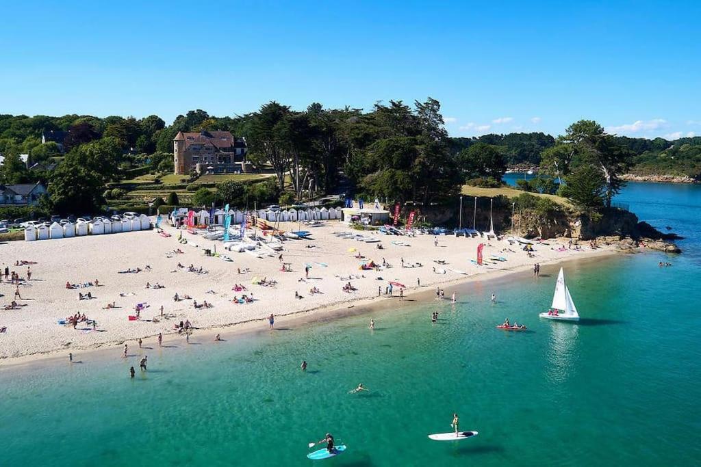 uma praia com pessoas e um veleiro na água em Une Chaumière à Port Manech' em Névez