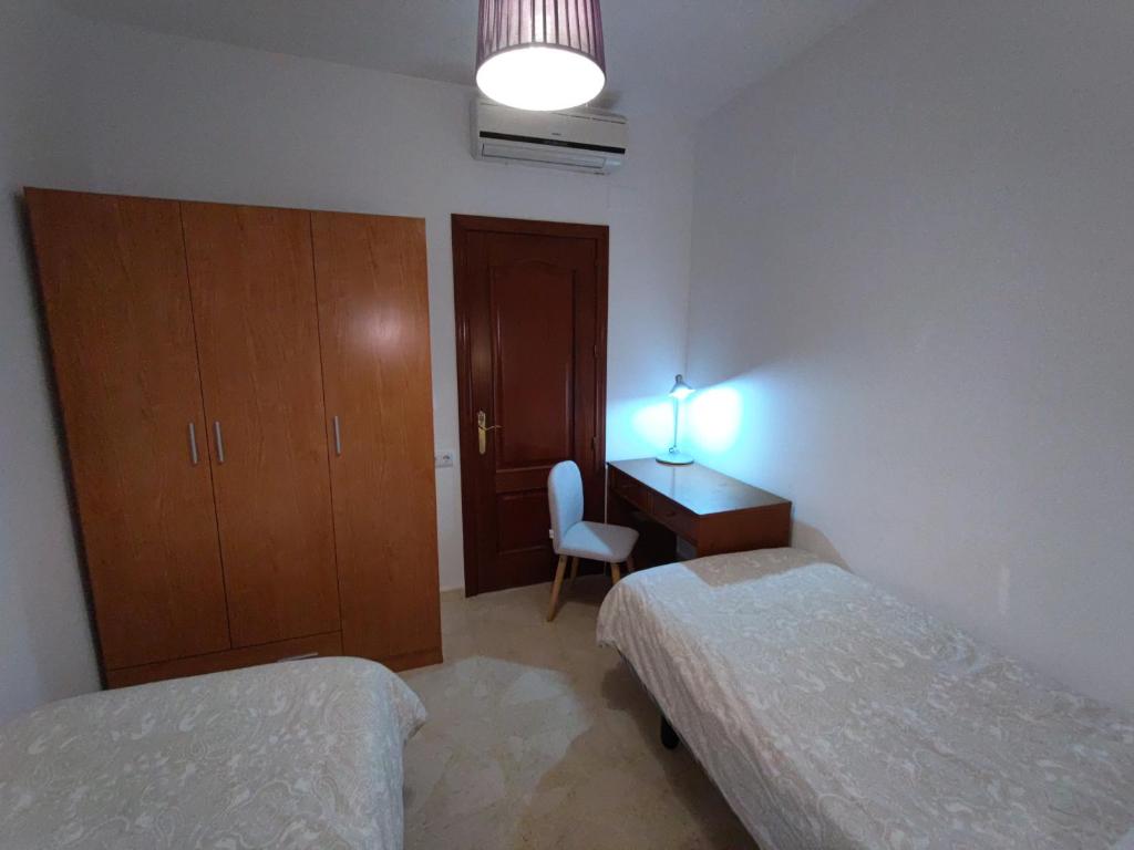 - une chambre avec deux lits, un bureau et une chaise dans l'établissement APARTAMENTO SEVILLA, à Alcalá de Guadaira