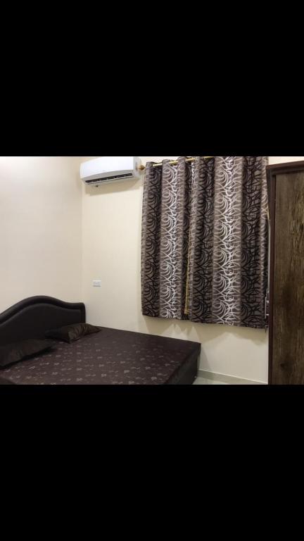 een kamer met een bed en een raam met een gordijn bij Athum أثوم in Ţāqah