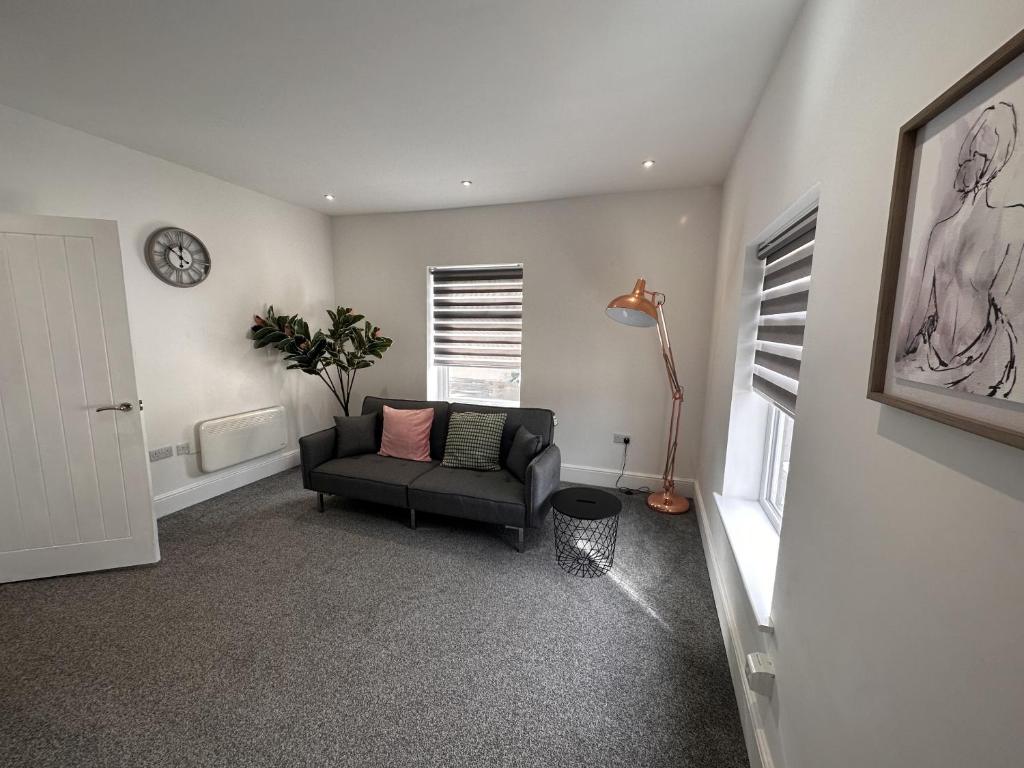 a living room with a couch and a clock on the wall at 50 Wood St in Burton upon Trent