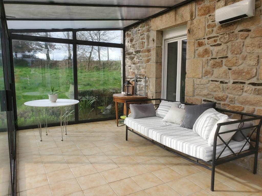 ein Wohnzimmer mit einem Sofa und einer Steinmauer in der Unterkunft Maison au calme Plessala Le Mené in Saint-Udy