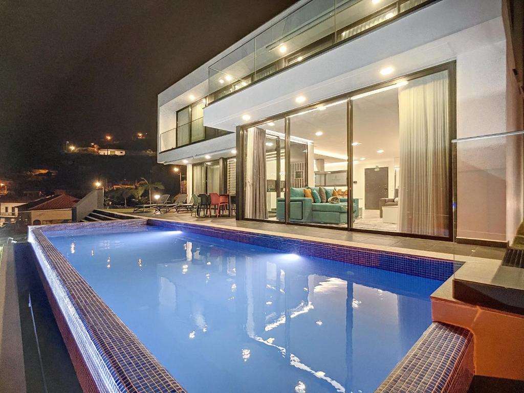 - une piscine en face d'une maison la nuit dans l'établissement Villa Ocean Haven by AH, à Ribeira Brava