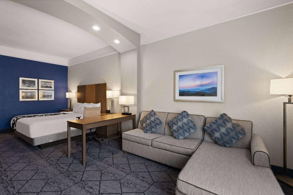a hotel room with a bed and a couch and a desk at La Quinta Inn and Suites by Wyndham at WaTiki Waterpark in Rapid City