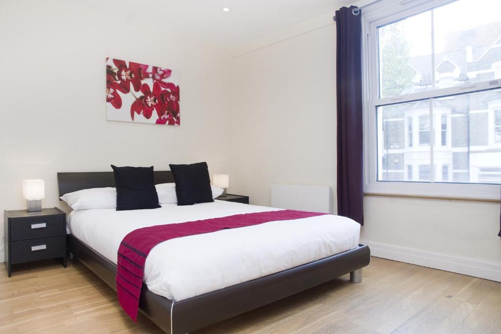 Un dormitorio con una cama grande y una ventana en Holiday Lets London K, en Londres