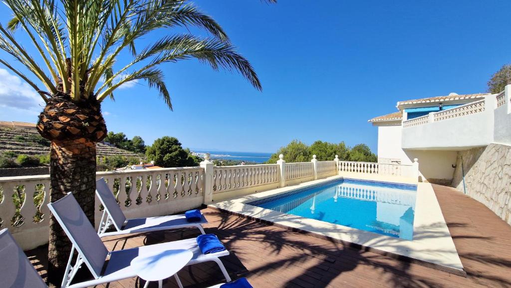 a villa with a palm tree and a swimming pool at Doble Diez in Denia