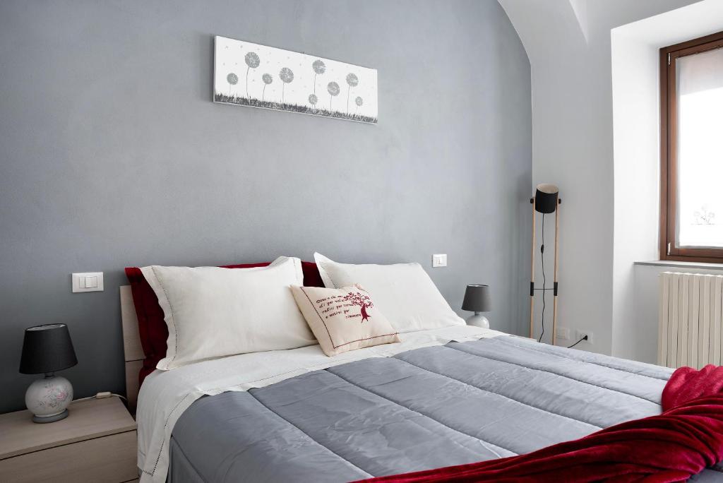 1 dormitorio con 1 cama grande con almohadas blancas en Casa Vacanze La Porta in Piazza, en Guarene