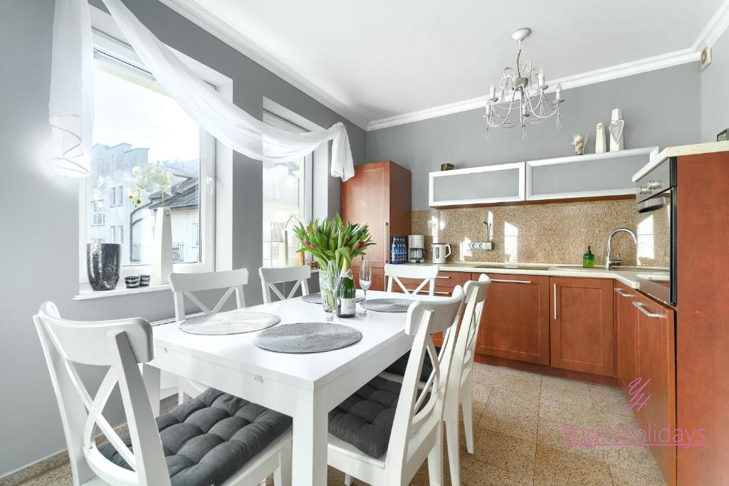 a kitchen and dining room with a white table and chairs at Your Holidays Gryfa Pomorskiego in Międzyzdroje