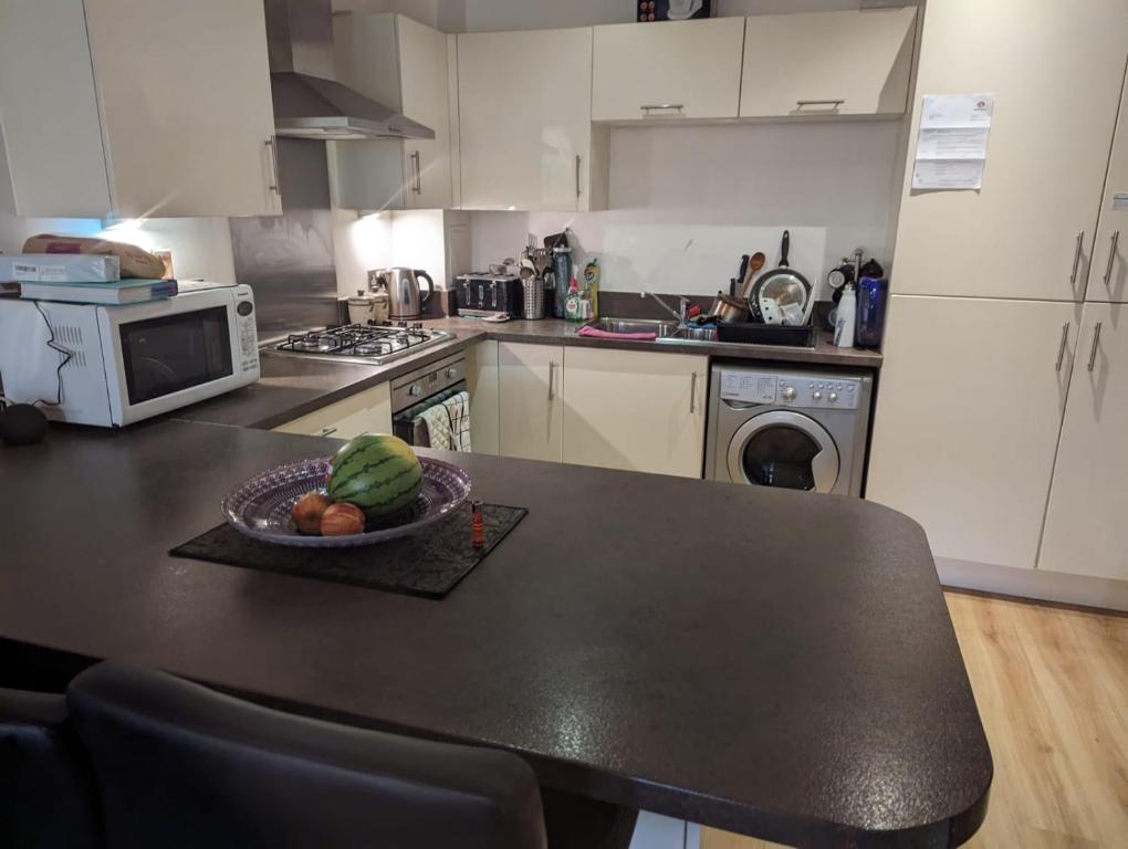 a kitchen with a table with a bowl of fruit on it at Charming bedroom in a shared 2-Bedroom Flat in Southall, London (next to Ealing Hospital). in London