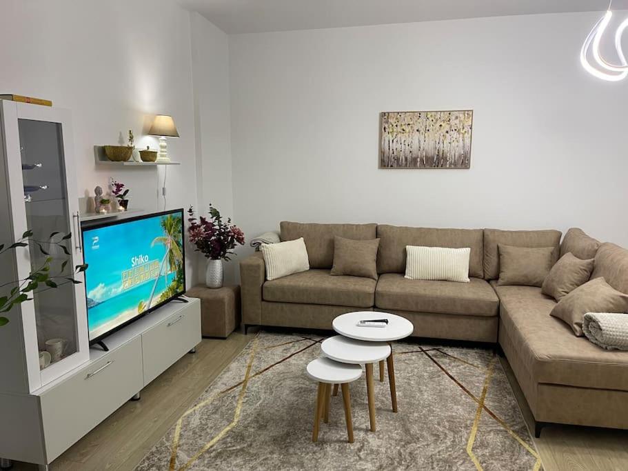 a living room with a couch and a tv and stool at Access apartment in Tirana