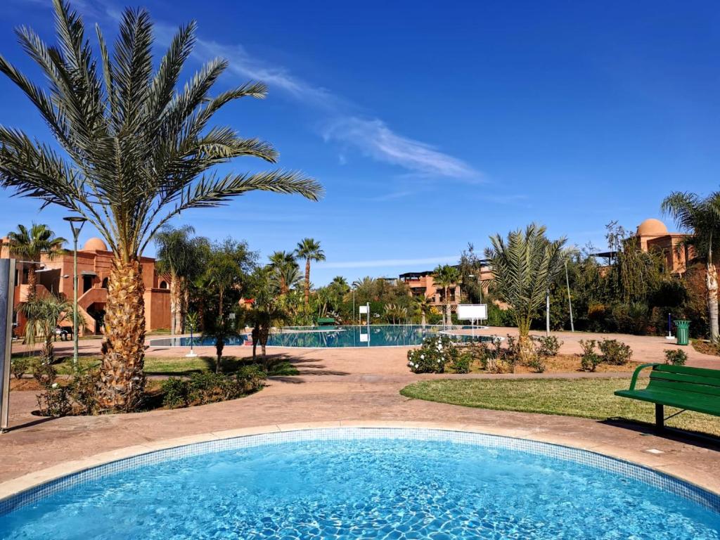 einen Pool mit einer Palme und einer Bank in der Unterkunft Cozy apartment with roof top in Marrakesch