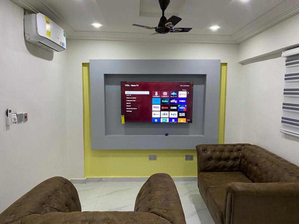 Kobbys Brands في تيما: غرفة معيشة مع كنبتين وتلفزيون بشاشة مسطحة