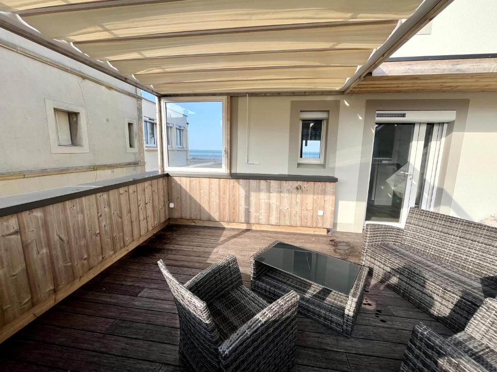 a balcony with two chairs and a glass table at La Tourelle - Balcon vue mer et terrasse plein sud in Saint-Aubin-sur-Mer