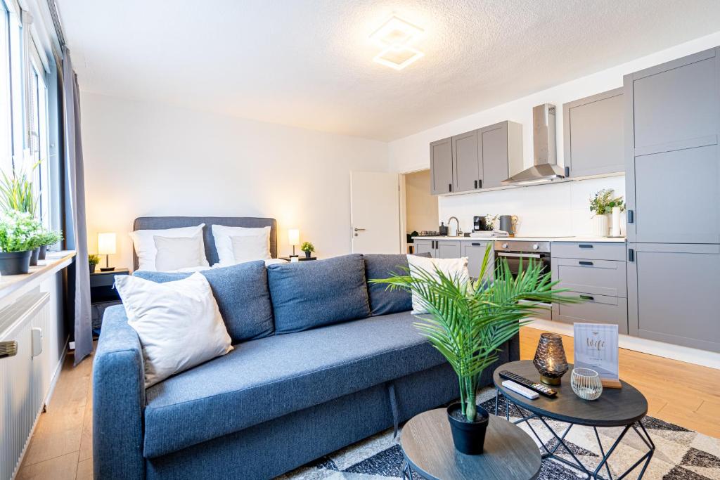 a living room with a blue couch and a kitchen at lionApartments Leverkusen in Leverkusen