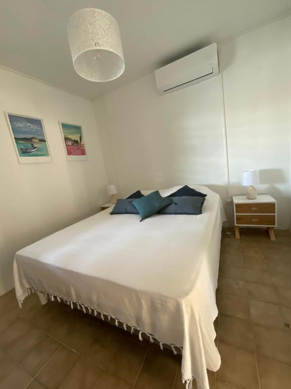 Un dormitorio con una gran cama blanca con almohadas azules. en Appartement Kay Nephile - vue mer - Grande Anse, en Les Anses-dʼArlet
