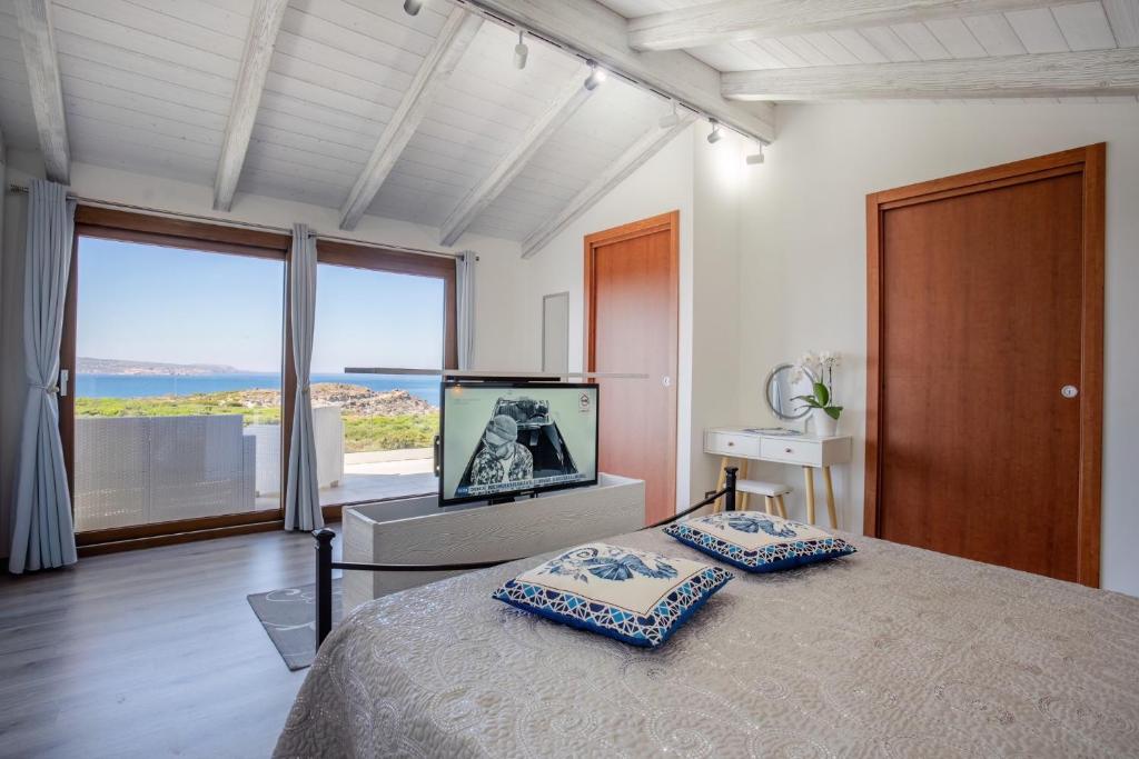 a bedroom with a television and a bed with pillows at B&B Le Ginestre in Portoscuso