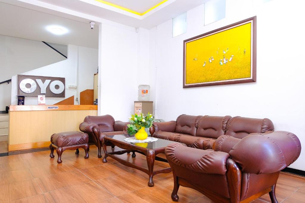 a waiting room with leather couches and a table at OYO 354' 32 Guest House in Batu