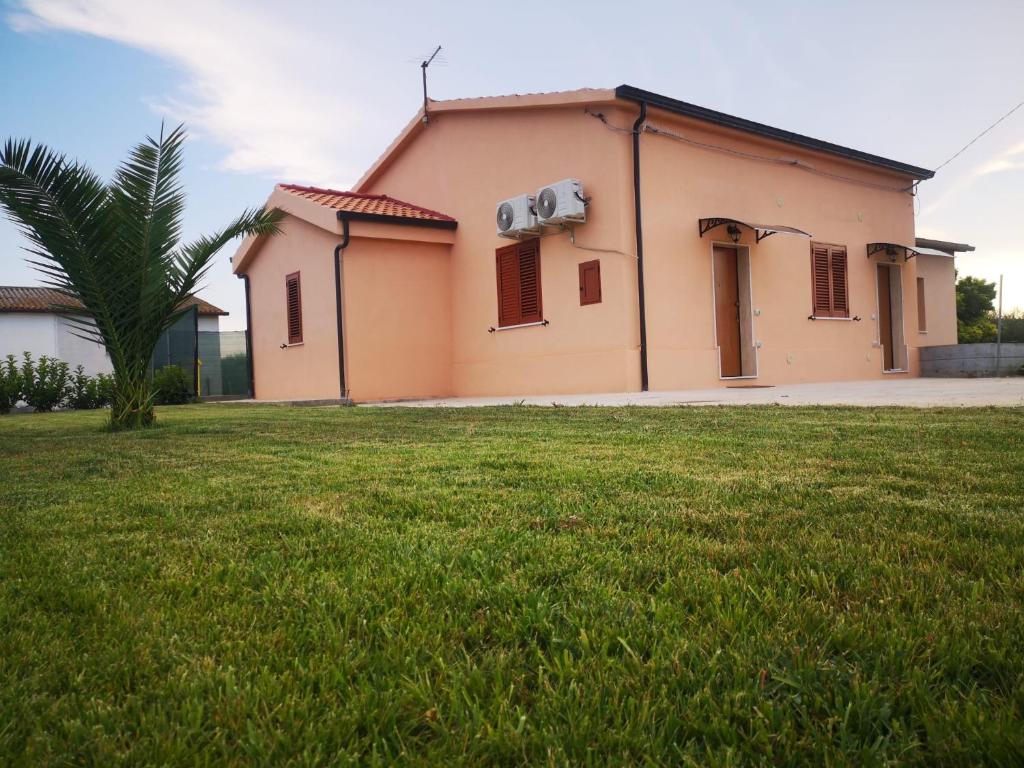 una casa con un campo de hierba delante de ella en Casa Vacanze Villa Annamaria, en Scanzano Jonico