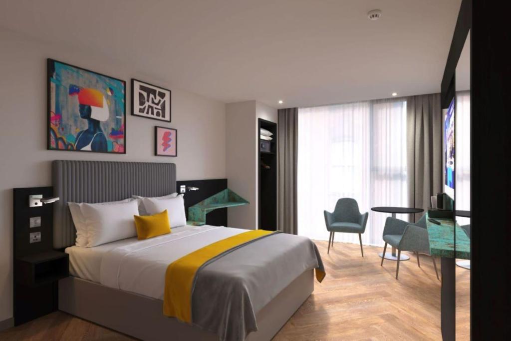 a hotel room with a bed and a table and chairs at Maldron Hotel Manchester Cathedral Quarter in Manchester