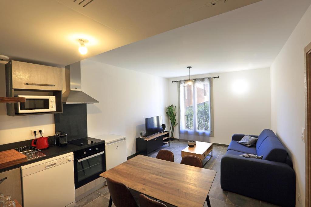 - une cuisine et un salon avec un canapé bleu et une table dans l'établissement Citadella Calvi T2 cosy et climatisé centre-ville, à Calvi