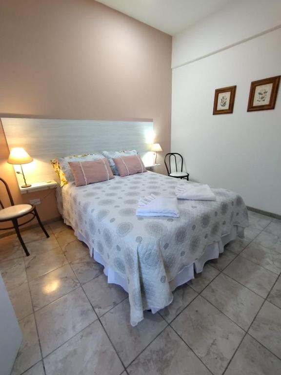 a bedroom with a large white bed with pink pillows at AMALIA departamentos in San Rafael